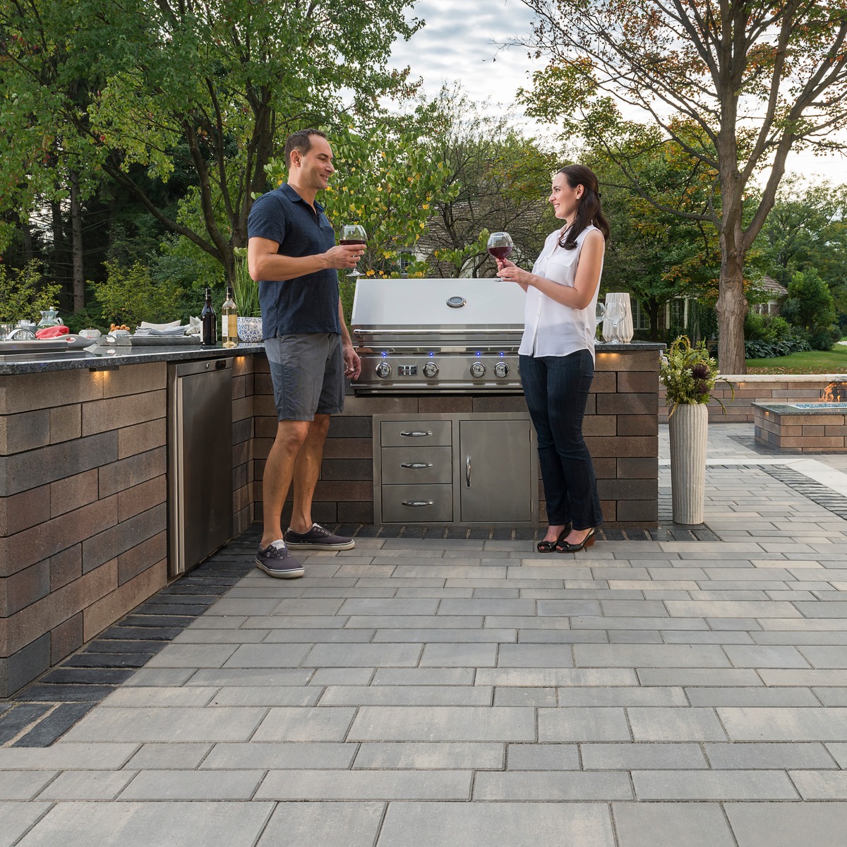 Couple enjoying wine at outdoor kitchen and paver patio