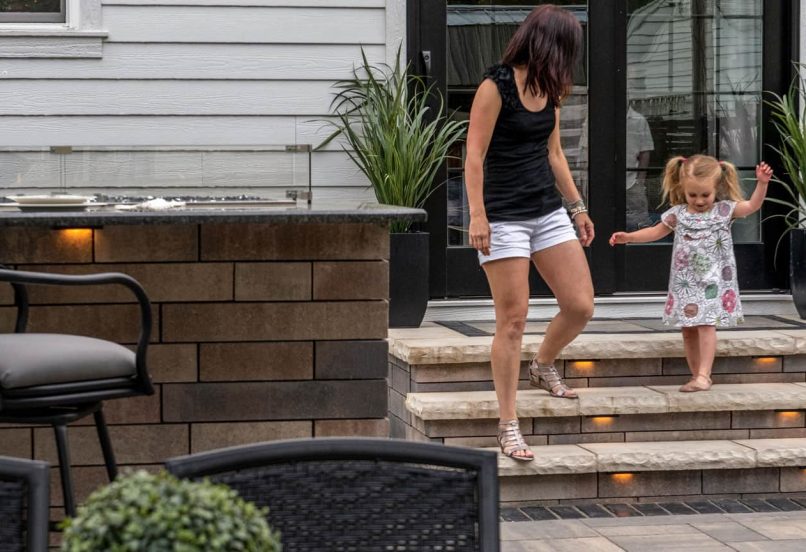 Person helping Young Child Walk down Unilock Steps with Lighting