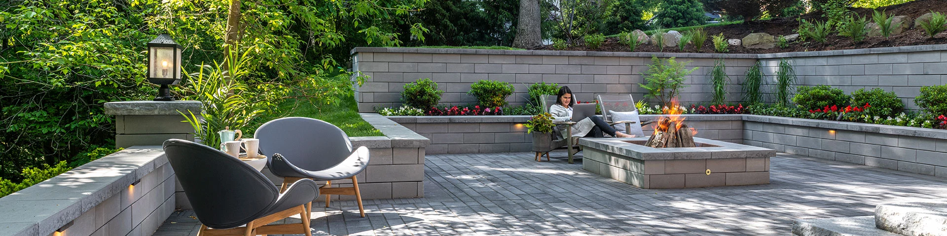 Person Lounging by Outdoor Fire Pit on Patio with Surrounding Retaining Walls