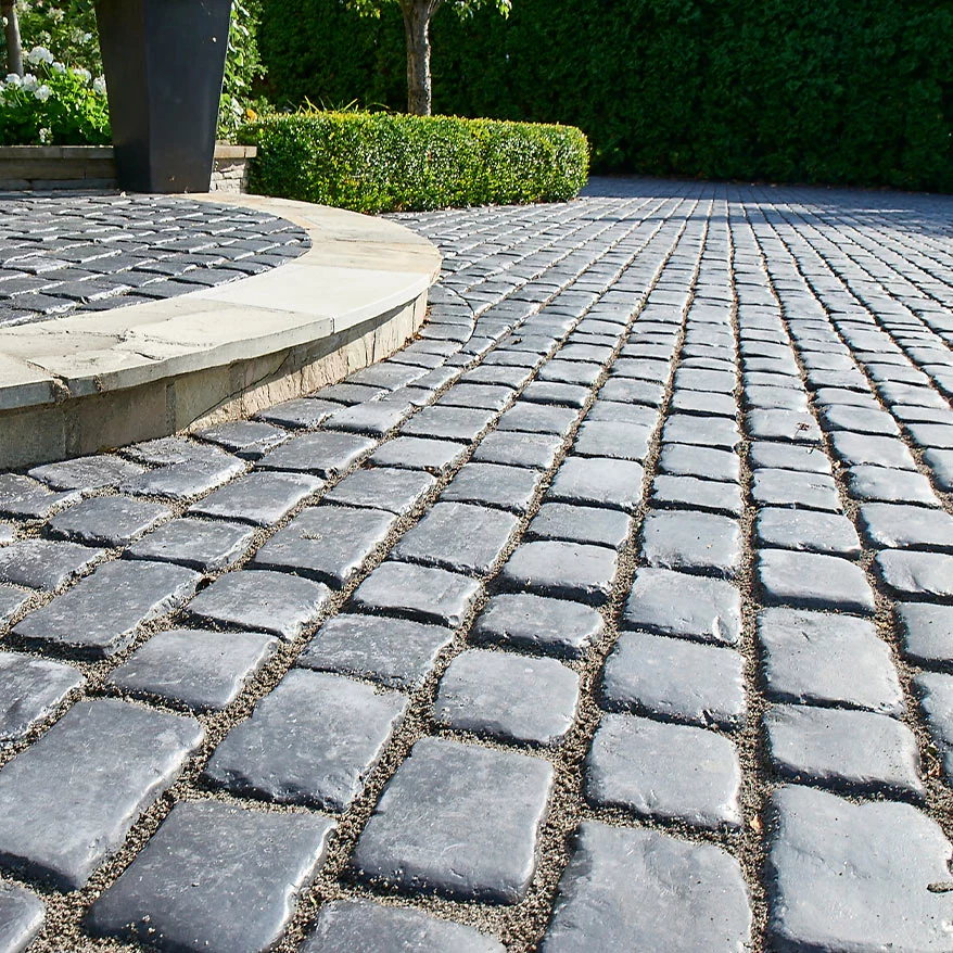 A walkway paved with Unilock landscape pavers in a garden.