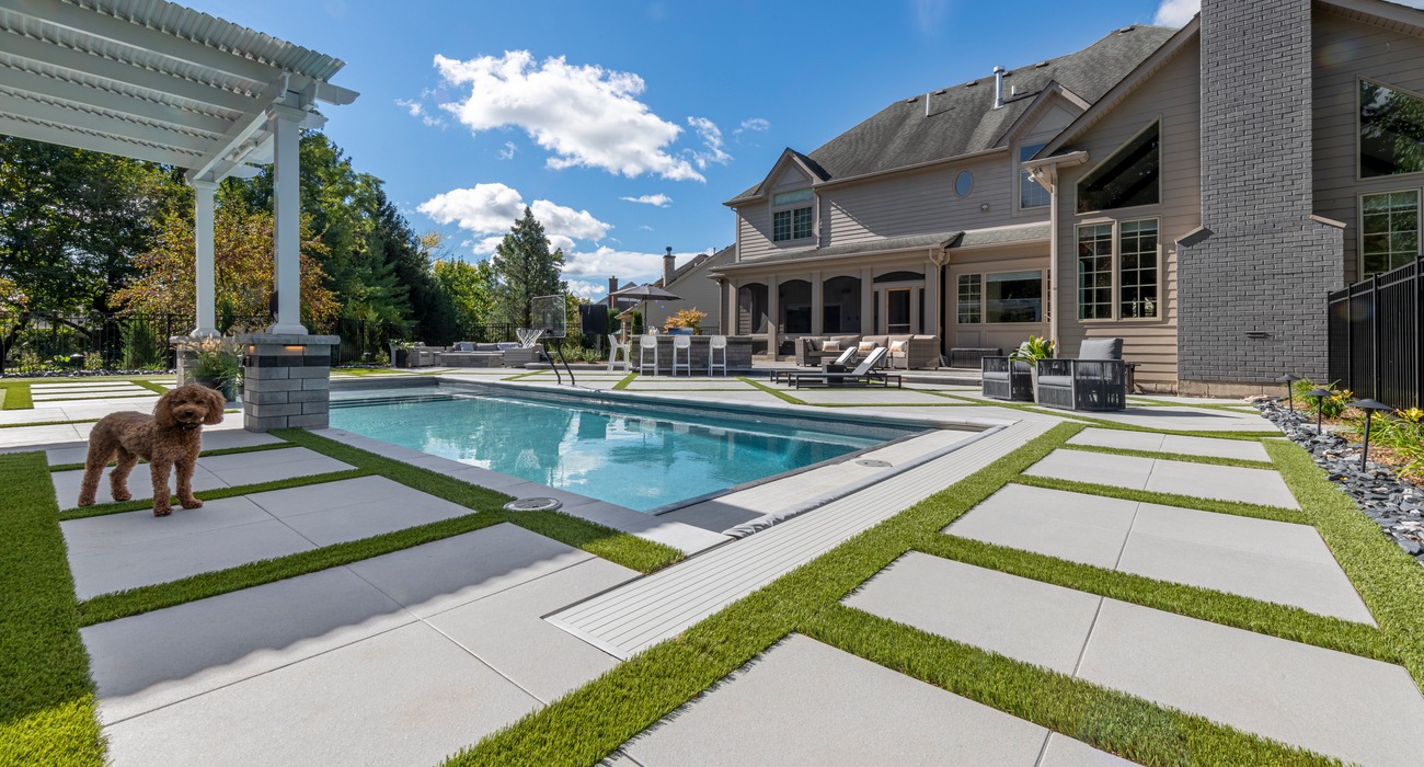 Dog standing on biophilic design inspired pool deck.